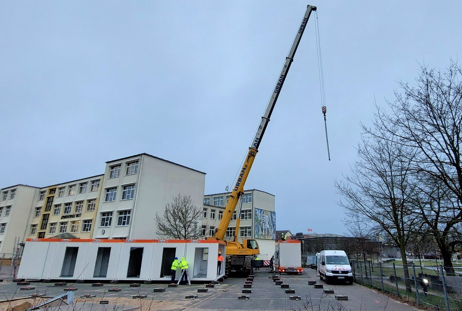 Baubeginn der GS West ein Kran stellt Mietcontainer auf