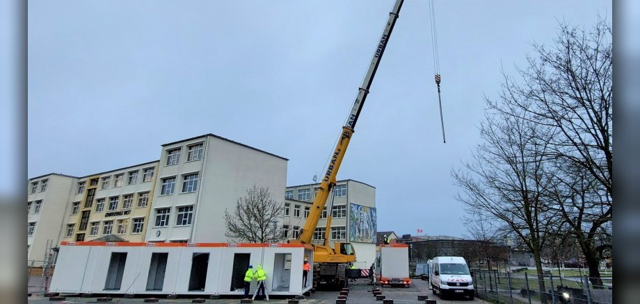 Baubeginn der GS West ein Kran stellt Mietcontainer auf