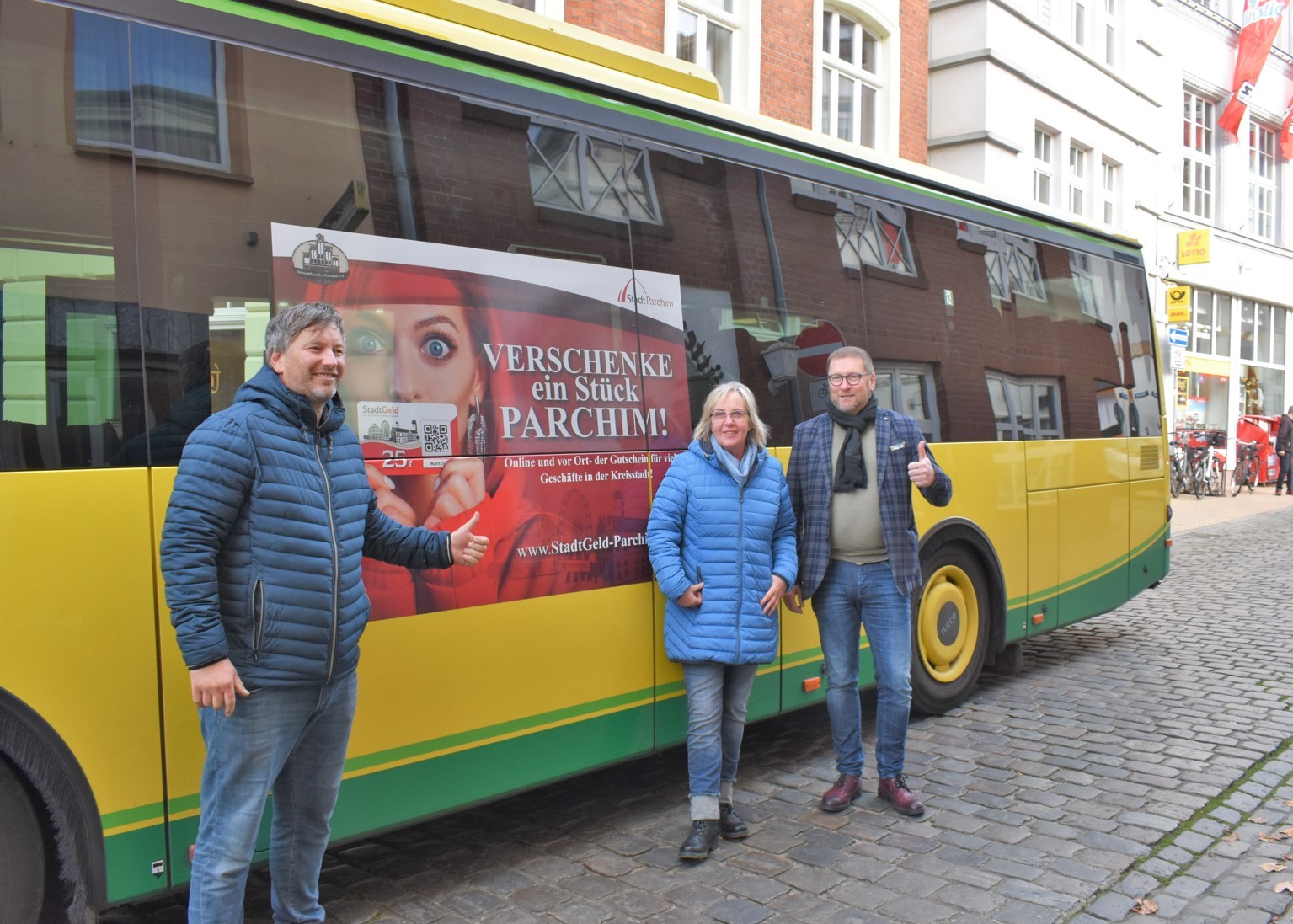 Birger Nickel (Zweirad Nickel), Kerstin Waschner (CeKa) und Bürgermeister Dirk Flörke präsentieren die Werbung auf dem Citybus für das Parchimer StadtGeld.
