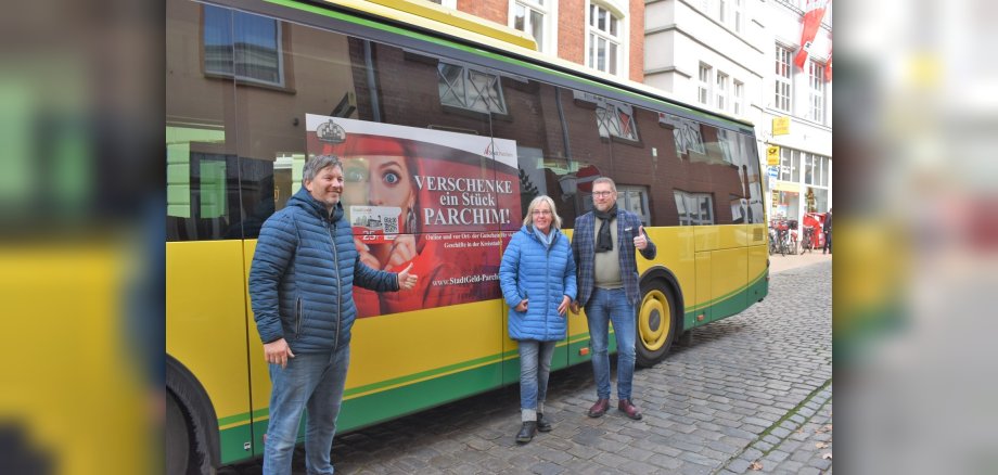 Birger Nickel (Zweirad Nickel), Kerstin Waschner (CeKa) und Bürgermeister Dirk Flörke präsentieren die Werbung auf dem Citybus für das Parchimer StadtGeld.